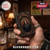 Ozzy Osbourne printed black metal lighter with ornate gold frame design held in a hand against a blurry bar background.!