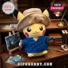 Pikachu plush toy wearing a tan hat and blue jacket, holding a paintbrush and palette near a miniature easel painting.!