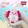 Pink crochet axolotl plush held in hands, holding a sign that reads: A tiny AXOLOTL is here to remind you you are loved.!