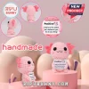 Handmade pink crocheted axolotl plush holding a white card with motivational text on a soft geometric display.!