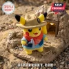 Pikachu plush toy wearing a tan explorer hat, blue vest, and red scarf, holding a gray pickaxe in front of a rock cave.!