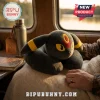 Umbreon Pokémon plush neck pillow with dark gray velvet texture, yellow rings, and red forehead crest on a blanket.!