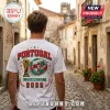 Man wearing white t-shirt featuring Portugal FIFA World Cup 2026 soccer ball and trophy graphic in a cobblestone street.!