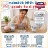 Crocheted light blue elephant plushie holding a white card with inspirational text, sitting on a wooden table.!
