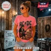 Woman wearing pink t-shirt with AC/DC Angus Young graphic, vintage concert style, standing in a studio with road cases.!