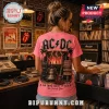 Pink AC/DC concert t-shirt featuring band logo, lightning, stage gear, guitar, and song titles on a brick record store wall.!