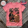 Pink cotton t-shirt featuring AC/DC logo, Angus Young playing guitar, and tropical signposts on a wooden background.!