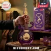Purple guitar-shaped glass decanter with gold hardware and Prince symbol, standing next to matching purple glass set.!