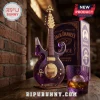 Purple guitar-shaped glass whiskey bottle with gold hardware, Prince symbol, and matching purple glass on wood table.!