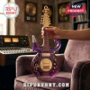 Prince Symbol purple glass guitar-shaped whiskey decanter with gold hardware held above a purple velvet chair.!