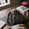 Tan fabric plush quadruped creature with teal polka dots sitting on a leather desk mat near a person sketching.!