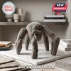 Grey felted fabric creature figurine with teal polka dots standing on a white marble slab on a neutral shelf surface.!