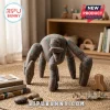 Grey felt four-legged creature plush toy with teal polka dots sitting on a woven circular rug in a nursery.!