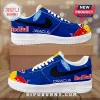Blue and white low-top sneakers featuring Red Bull, Oracle, and Ford logos with yellow toe accents and black swooshes.!