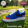 Blue sneaker with Oracle Red Bull Racing branding, yellow toe cap, Ford logo, and white laces on grass background.!