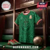Green Mexico soccer jersey with Aztec patterns, red and white trim, hanging in a locker next to matching cleats and ball.!
