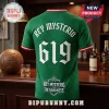 Green Rey Mysterio soccer jersey featuring white 619 text and Aztec calendar pattern on a wooden bar counter background.!