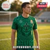 Man wearing a green jersey with Aztec-style patterns, a central cross icon, and Mexico text on a soccer field.!