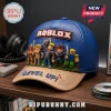 Blue and tan baseball cap featuring a Roblox logo, 3D character figures, and text on a wooden surface.!