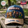 Blue and beige baseball cap featuring a 3D Roblox logo and various character figurines on a wooden park bench background.!
