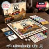 Route 66 100th Anniversary Monopoly game board with paper money, dice, metal tokens, and box on wooden table.!