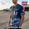 Man wearing a navy blue RCAF baseball jersey with fighter jet graphics, Canadian flag patch, and custom name placeholder.!