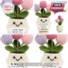 Crocheted tulip plant with a smiling face holding a sign reading I love you, featuring purple and pink yarn flowers.!