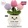 Crochet potted plant with lavender, dark pink, and light pink flowers held by a white smiling yarn pot for an aunt.!