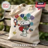 Beige canvas tote bag featuring embroidered Snoopy holding flowers and heart with colorful autism puzzle piece motifs.!