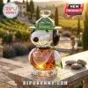 Snoopy crystal figurine wearing a green hat with 1950-2025 75th anniversary text engraved on the amber colored body.!