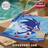 Blue Sonic the Hedgehog beach towel with text reading Running Since 1991 and a golden ring on a wicker poolside chair.!