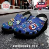 Blue Sonic the Hedgehog foam clogs with attached Jibbitz charms of Sonic, Tails, and Chao characters on a street background.!