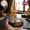 Spain 2026 World Cup Champions gold trophy keychain with Spanish flag emblem held in a hand against an office background.