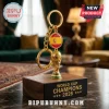 Spain 2026 World Cup Champions gold trophy keychain with a Spanish flag emblem resting on a wooden base.
