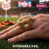 Spain National Football Team 2026 World Cup Champions gold ring featuring a trophy emblem on a finger over a grass field.