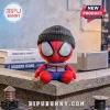Spider-Man Brand New Day Beanie Plush Toy wearing a charcoal gray knit cap and iridescent goggles on a textured ledge.