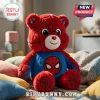 Superhero Bear Plush Doll in red and blue with a spider-web pattern, seated on a textured rug in a soft-focus room.