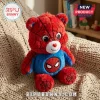 Superhero Bear Plush Doll in red and blue fabric with black spider web patterns sitting on a beige knitted blanket.
