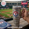 Texas Rangers metal tumbler with rhinestones, team logo, baseball motifs, and metal straw held at a baseball stadium.!
