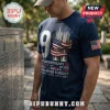 Th Anniversary We Will Never Forget T-Shirt in navy blue featuring a 9/11 twin towers graphic and an American flag patch.