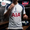 White Tottenham Hotspur soccer jersey with navy blue sleeves and red AIA logo, worn by a man in a locker room setting.!