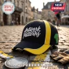 Black and yellow baseball cap with Artwork patterns white script text and green cycling jersey side patch on cobblestones.!