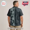 Man wearing a charcoal grey button-up shirt with light grey tropical leaf patterns and a vertical geometric stripe design.!