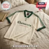 Cream v-neck jersey with dark green trim, Chavarria text in gothic font, and dual trefoil logo on a beige bedspread.!