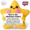 Yellow crochet star plush toy with pink cheeks holding a white sign that reads And so the adventure begins.!