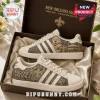 Adidas New Orleans Saints Who Dat Nation casual shoes featuring gold fleur-de-lis and mascot graphics in a display box.
