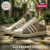 Adidas New Orleans Saints Who Dat Nation casual shoes featuring beige leather, team logo, and gold mascot illustrations.