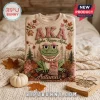 Alpha Kappa Alpha Sorority Frog Mascot Autumn Ugly Sweater in cream with embroidered green frog, leaves, and AKA lettering.