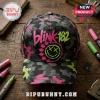 Blink-182 Neon Smiley Camo Cap featuring a gray, pink, and green camouflage pattern with embroidered band logo and icon.