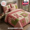 Breast Cancer Awareness Quilted 3-Piece Bedding Set with pink ribbons, floral appliques, and green accents on a bed frame.